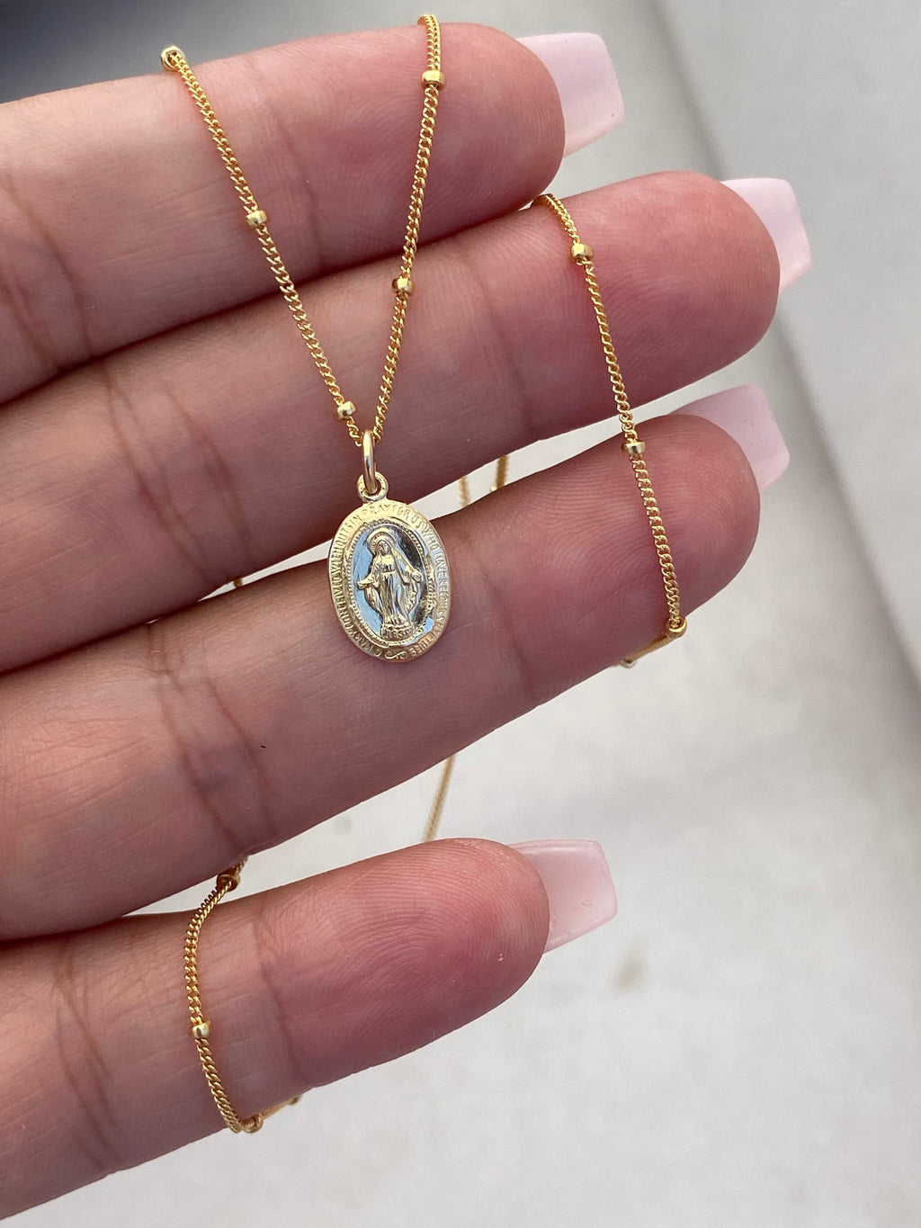 Gold-tone medal necklace with oval pendant and textured edge