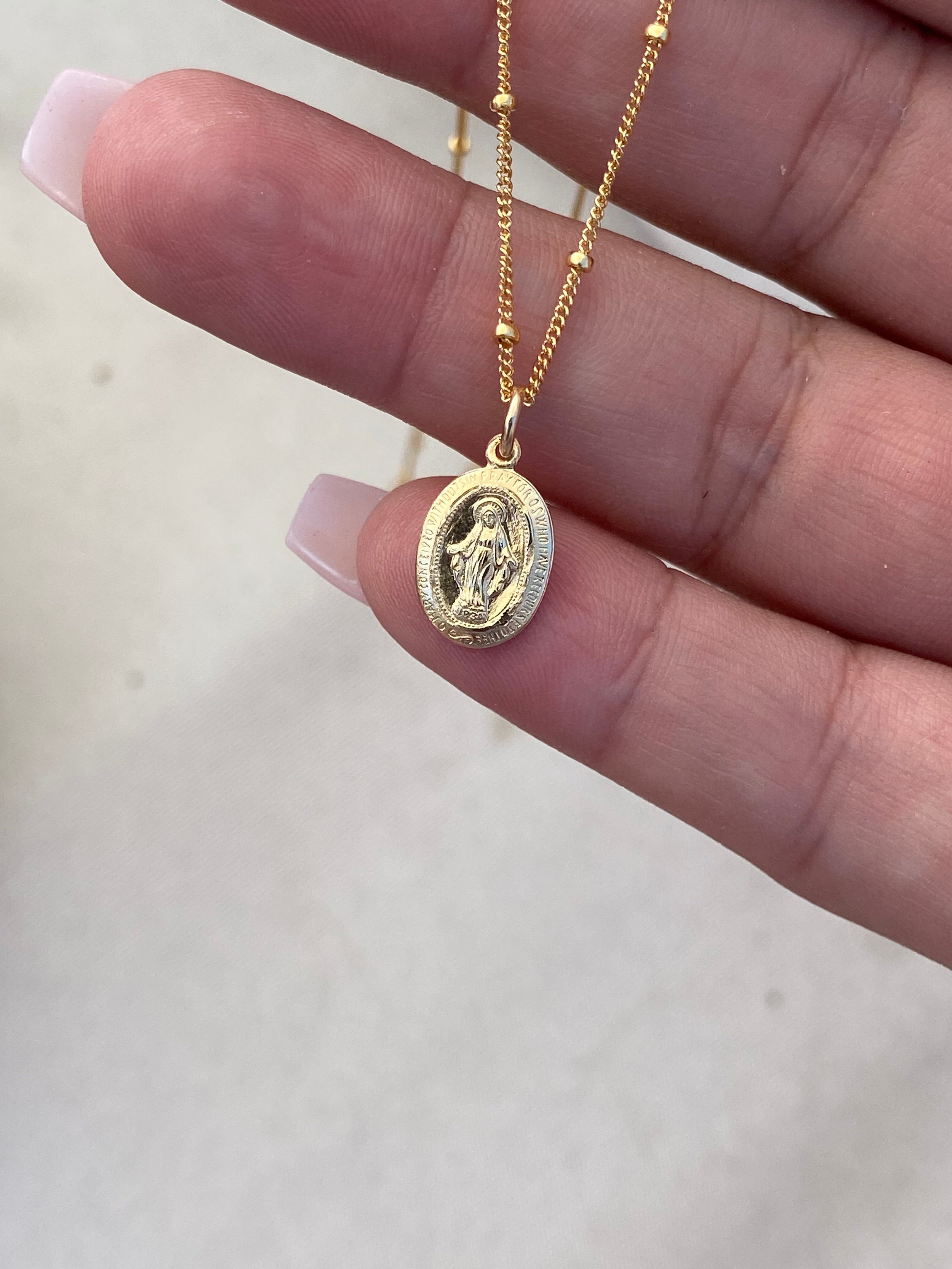 Gold-tone medal necklace with oval pendant on a fine chain