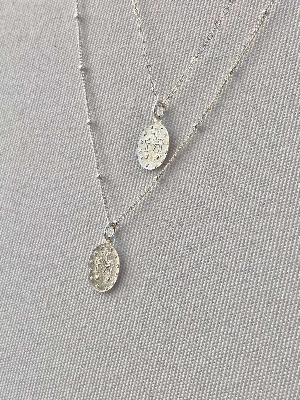 Silver miraculous medal necklaces, two oval pendants on thin chain