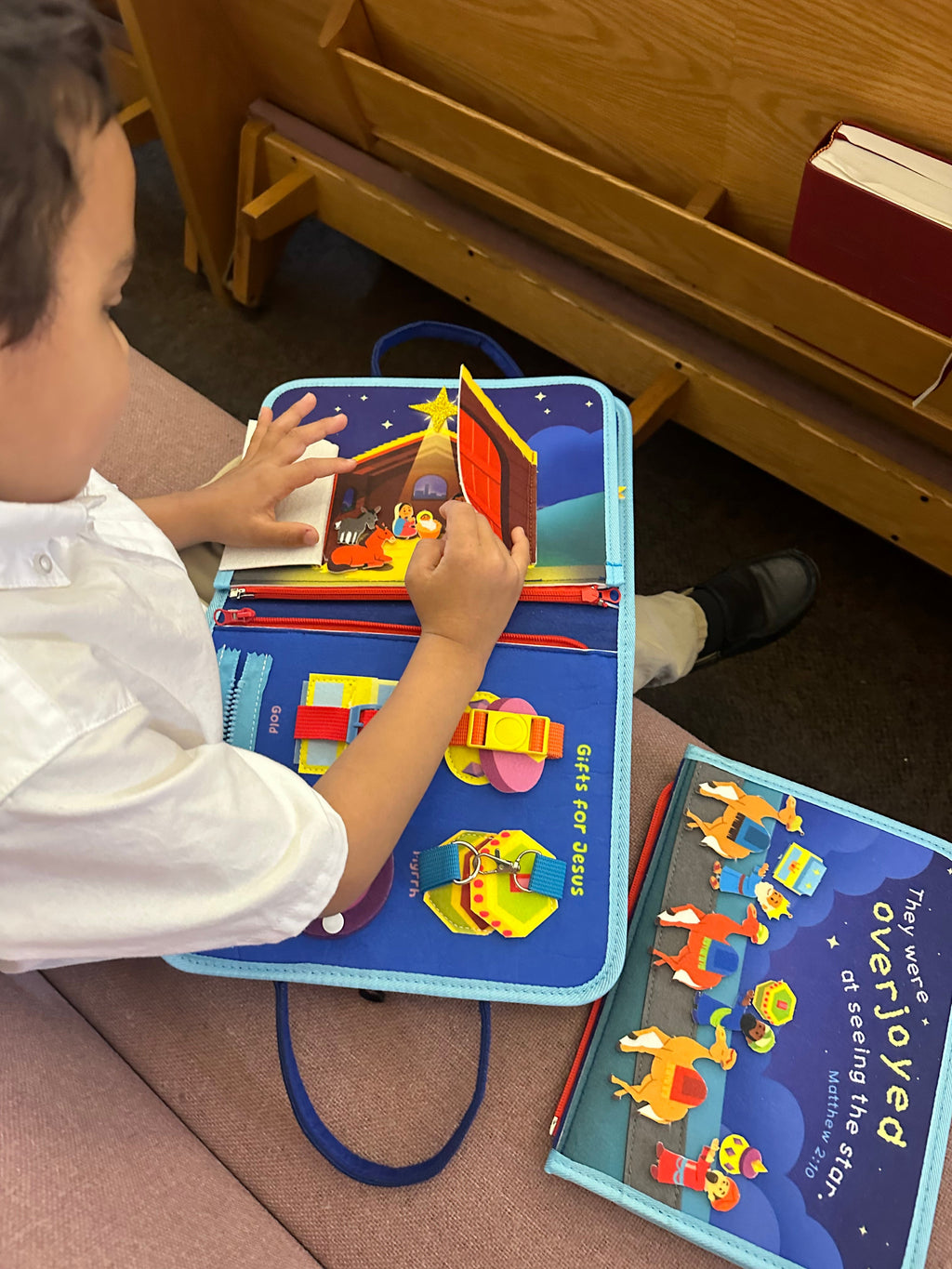 Child using nativity busy book on the floor with star nativity scene and felt activities