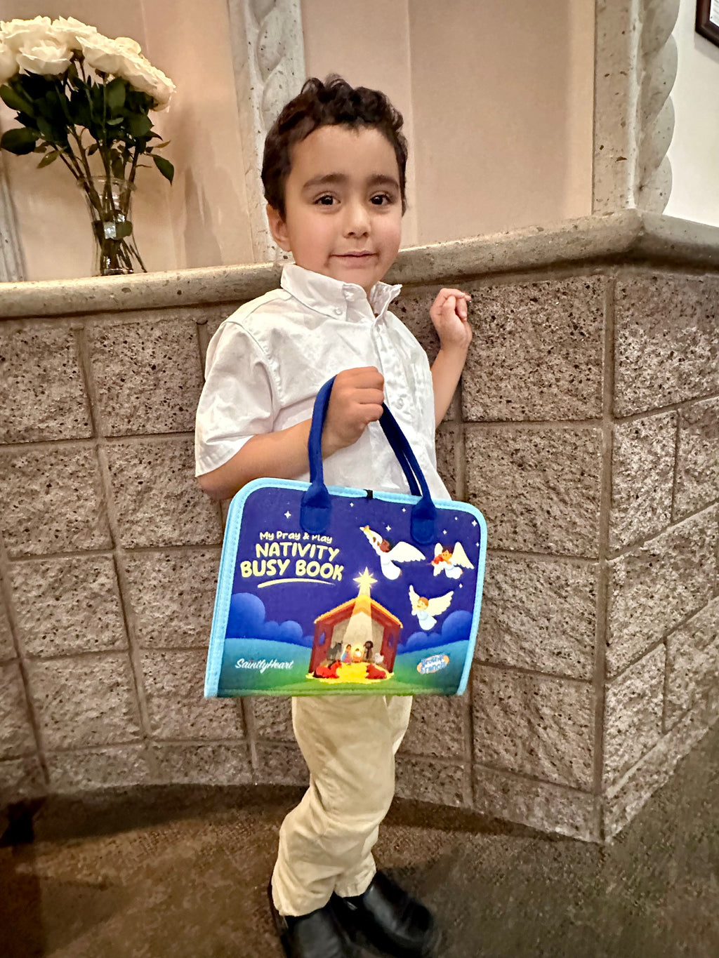 Child holding a blue nativity busy book with angel and manger cover