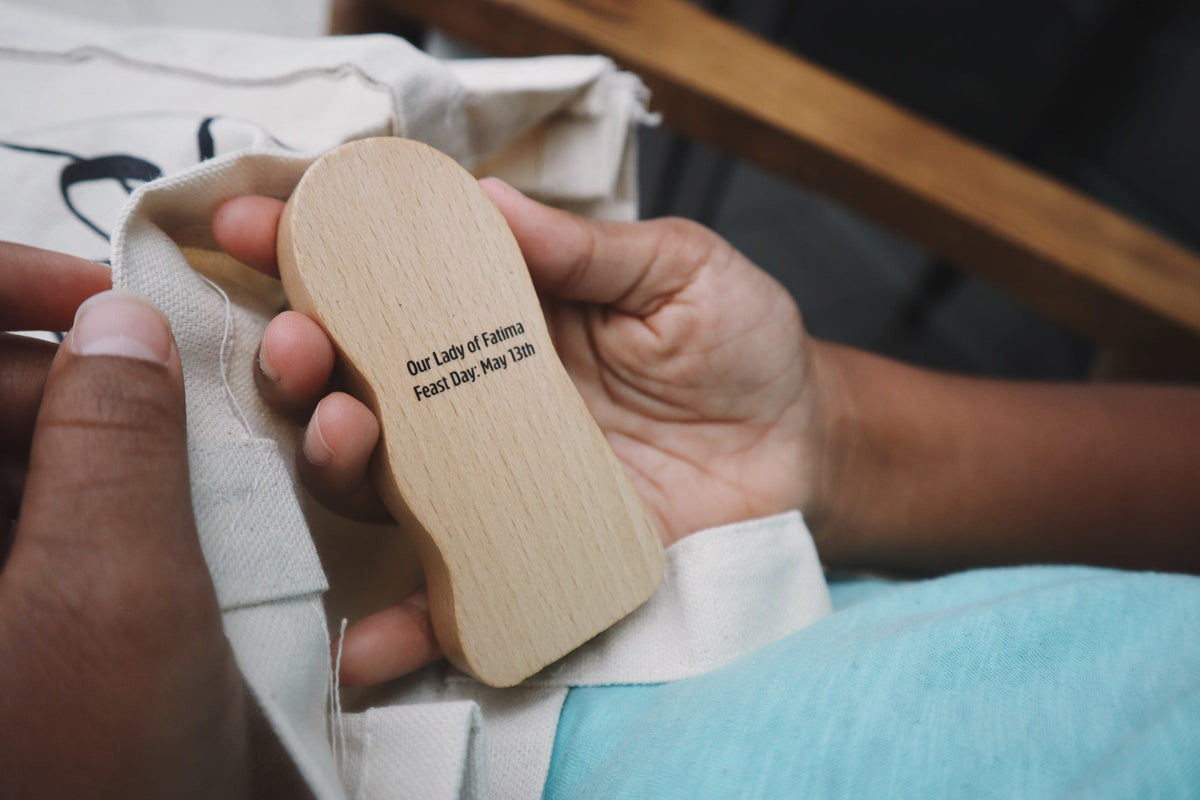 Hand holding wooden heart-shaped keepsake with engraved prayer text