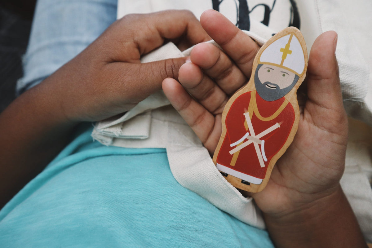 Single painted religious wooden peg figure of a bishop in red robe, held in hand