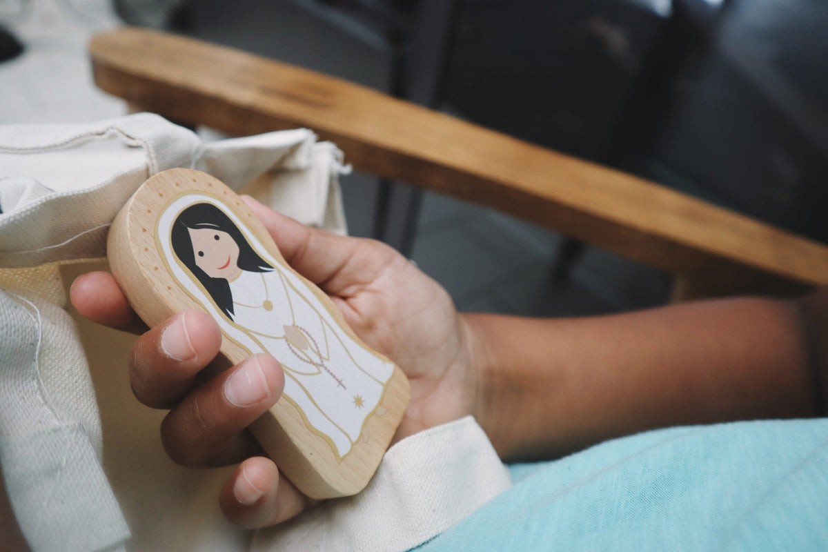 Wooden saint figure cutout held in hand, woman in prayer stance