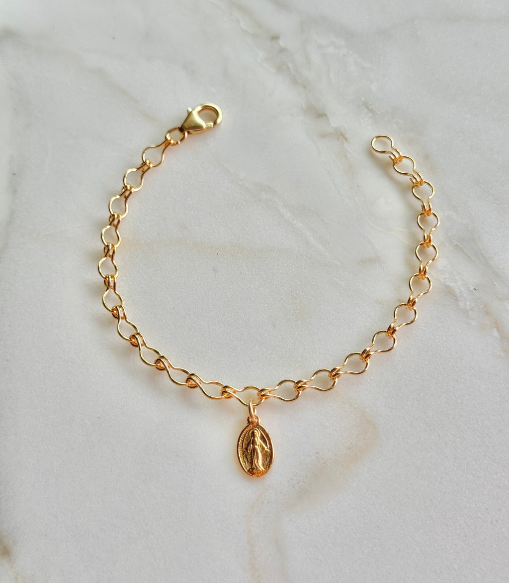 Gold-tone bracelet featuring an oval medal charm on a curved linked chain