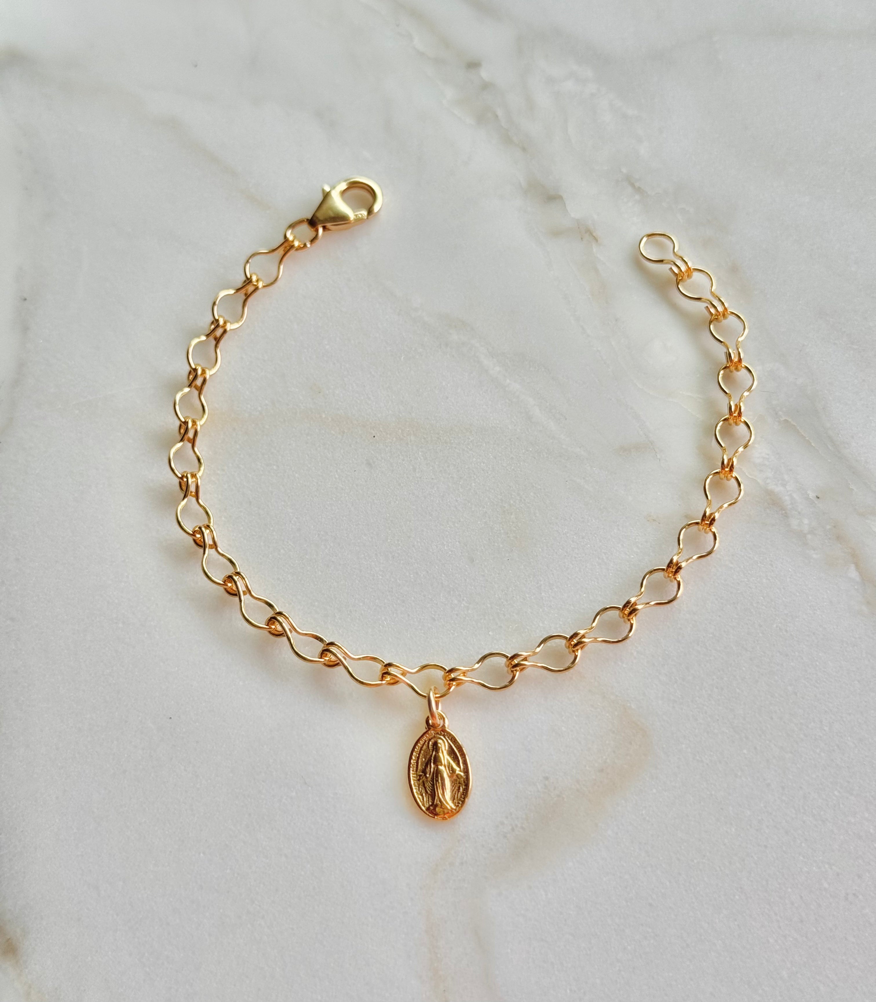 Gold-tone bracelet featuring an oval medal charm on a curved linked chain