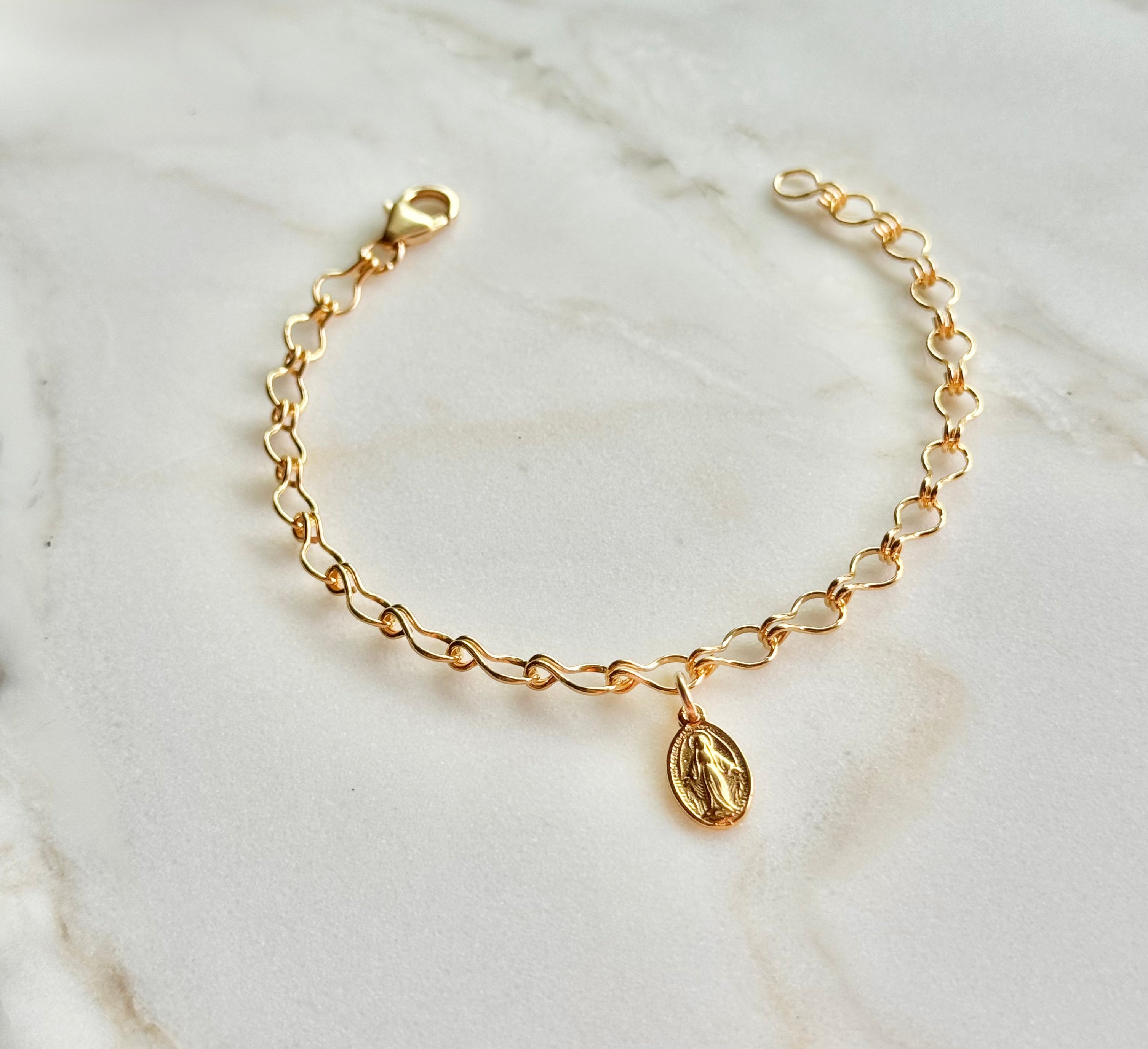 Gold-tone bracelet with oval medal charm and lobster-style clasp at top