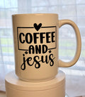 Beige ceramic coffee mug with black text: COFFEE AND Jesus and a heart logo