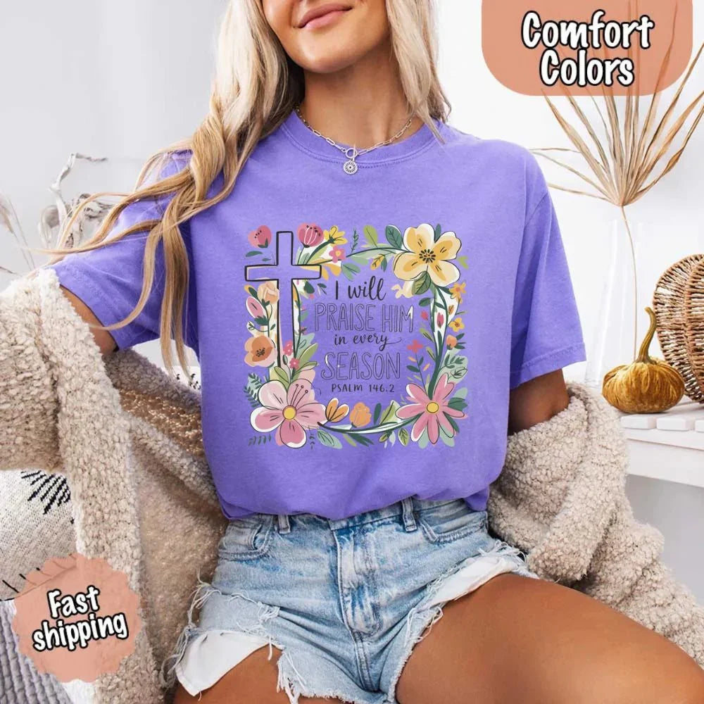 Purple crewneck tee with floral cross wreath and “I will praise Him in every season”