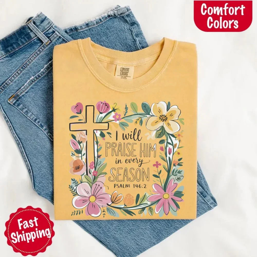 Yellow/gold crewneck tee with floral cross and blooms, “I will praise Him in every season”