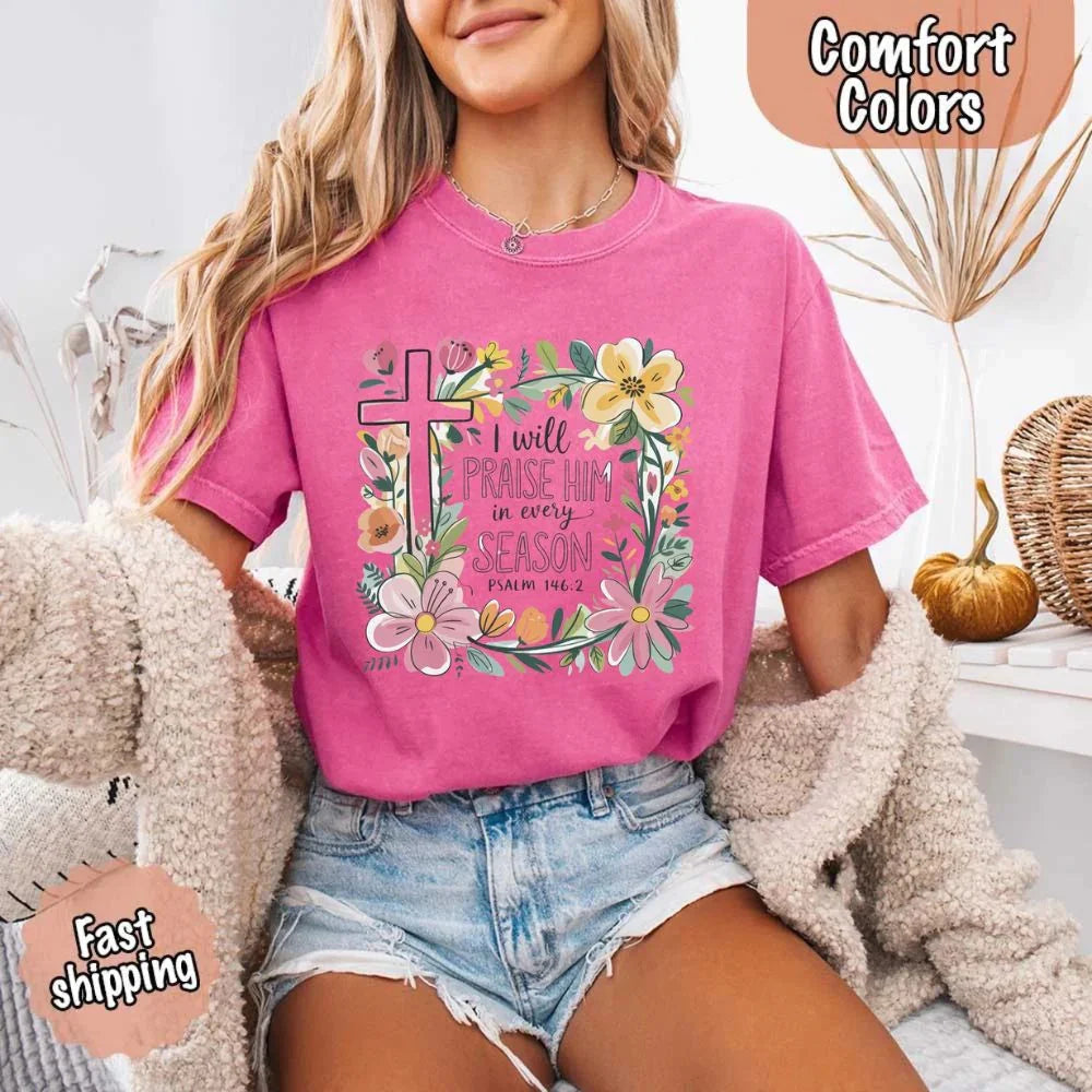 Pink/magenta crewneck tee with floral cross and flower frame, “I will praise Him in every season”