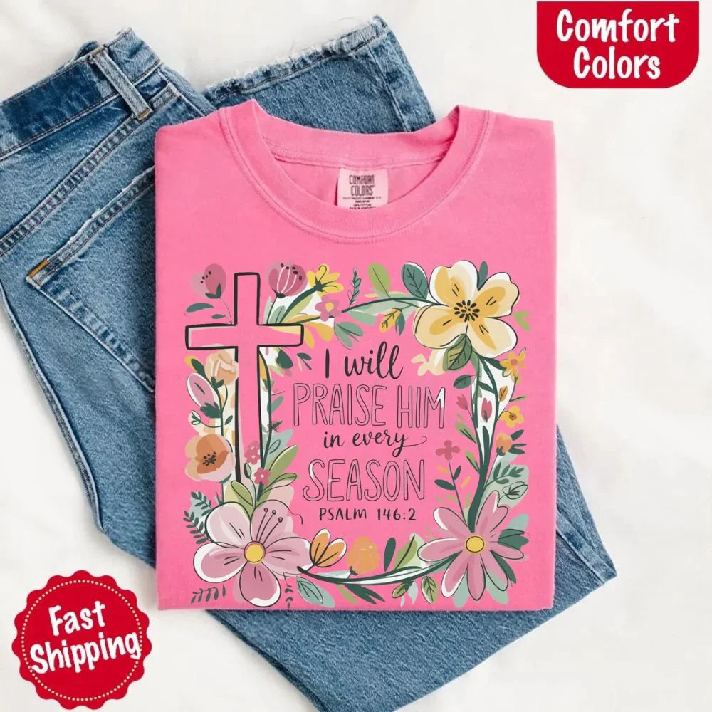 Pink comfort tee with floral cross and “I will praise him in every season” graphic