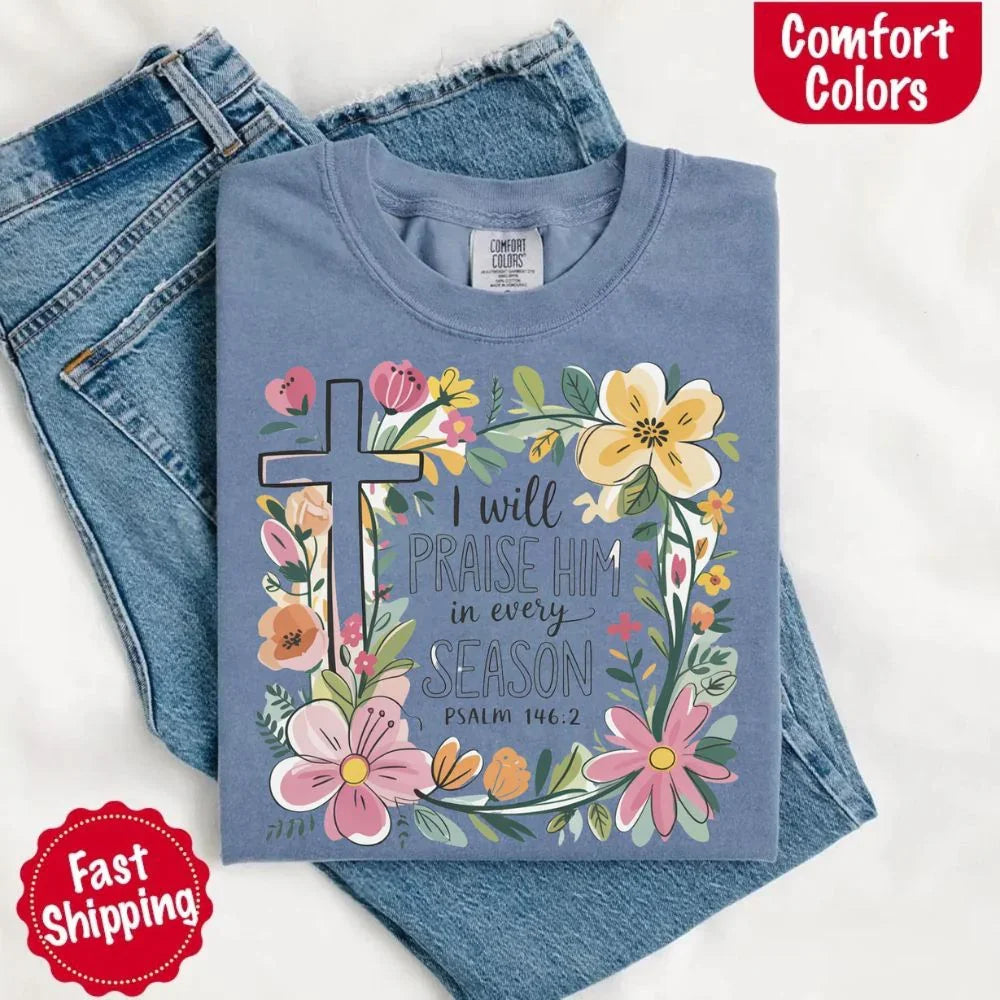 Slate blue comfort tee with floral cross and “I will praise him in every season” design