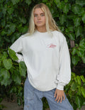 White long-sleeve unisex tee with small red script logo on the chest