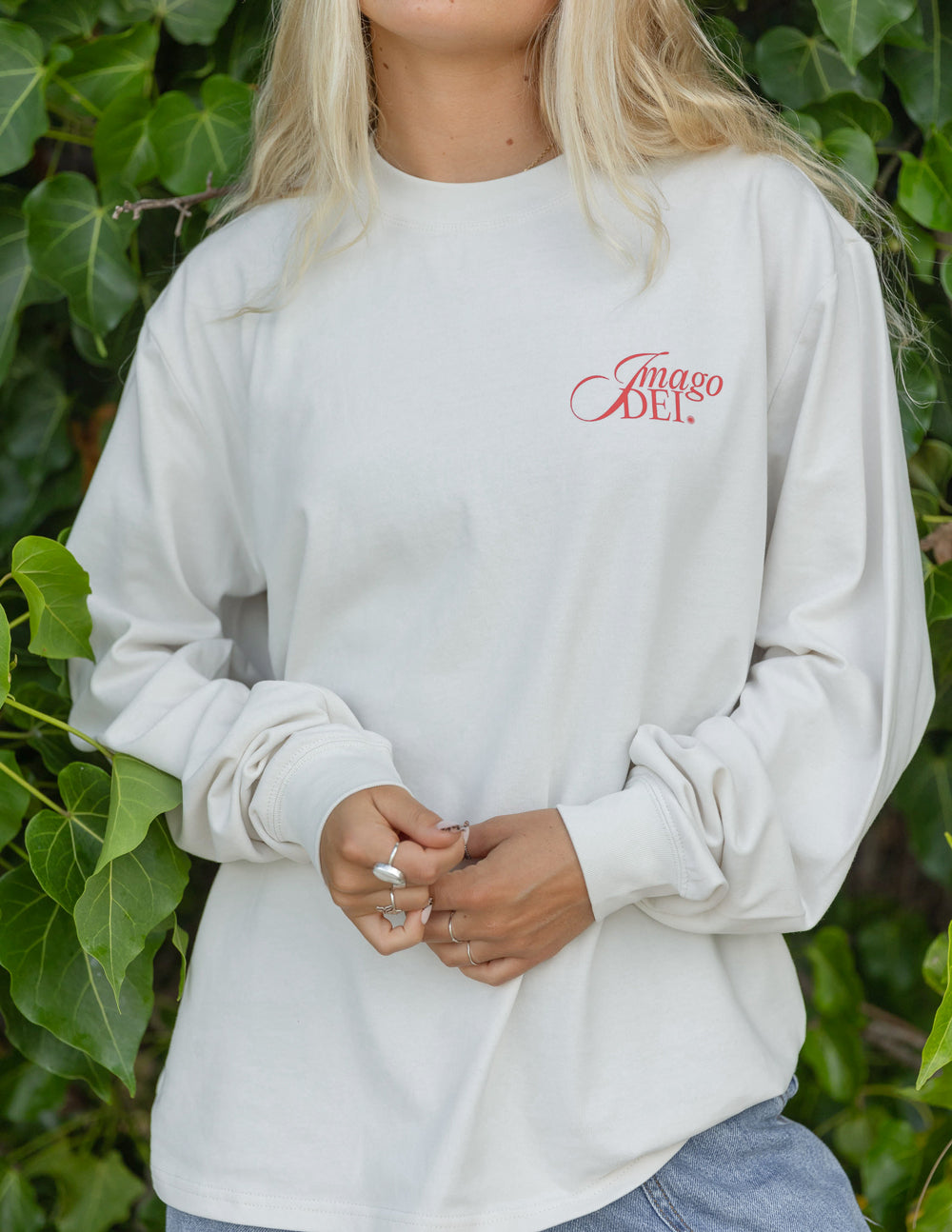 White long-sleeve unisex tee with small red chest logo; loose fit sleeves