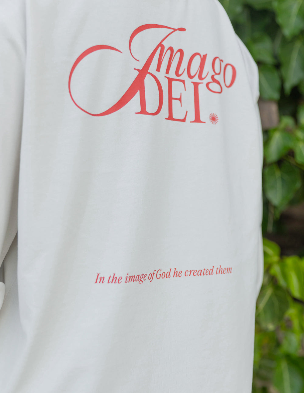 White long-sleeve unisex tee close-up with red script logo and small text