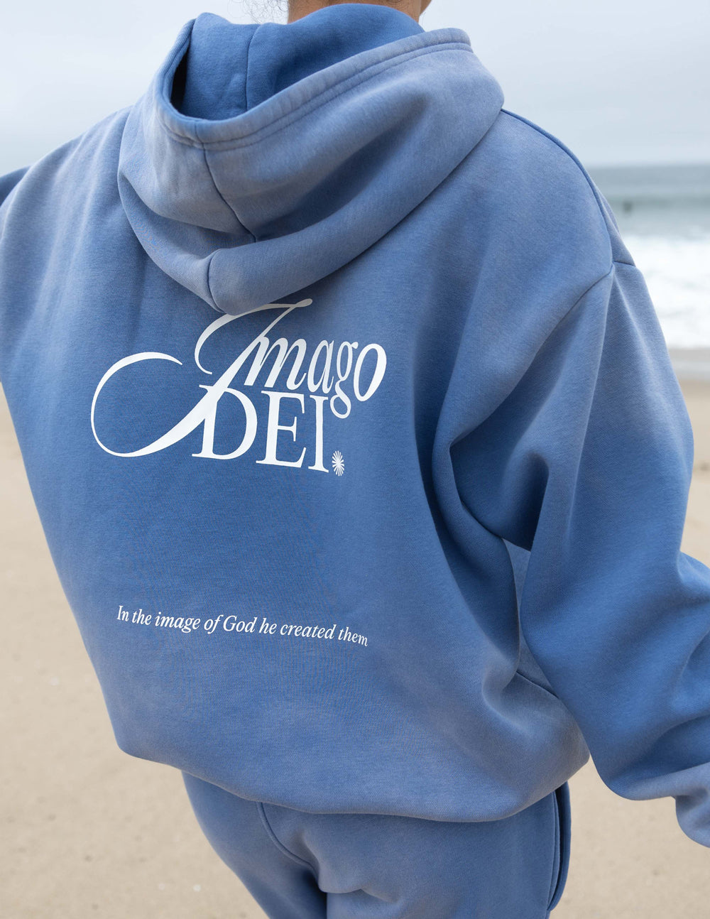Blue unisex hoodie, back view with large Imago DEI logo and small tagline