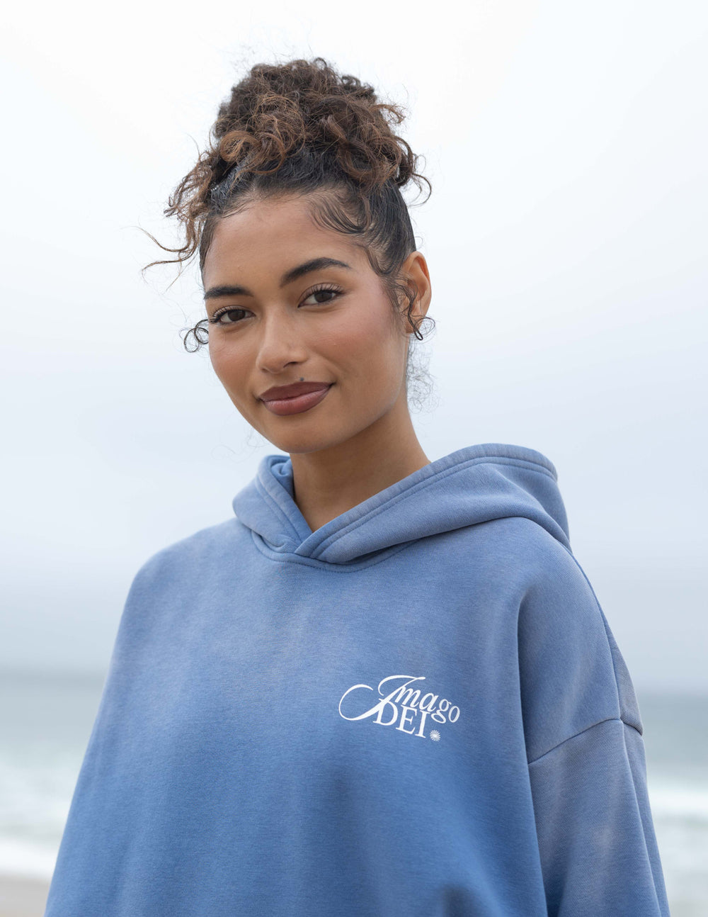 Blue unisex hoodie with hood and front Imago DEI script logo