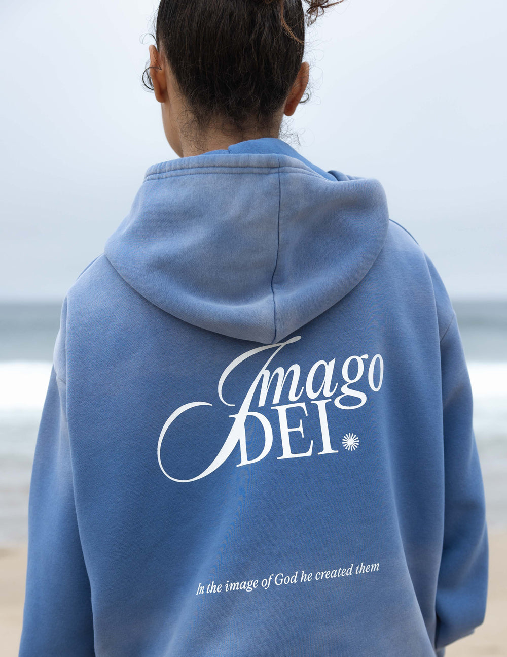 Blue unisex hoodie back with large Imago DEI script logo and hood