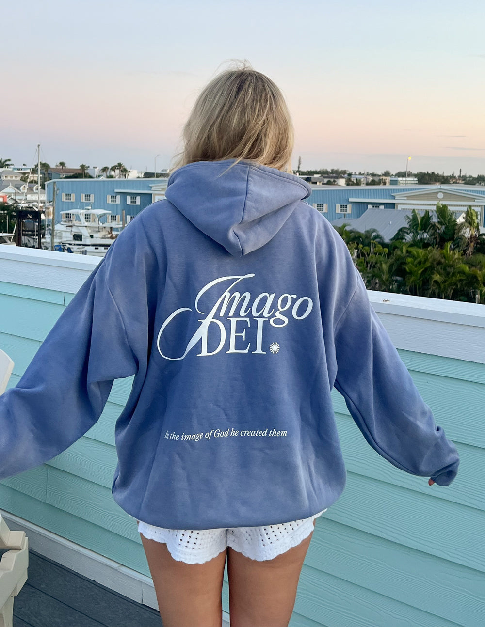 Blue unisex hoodie back with Imago DEI logo and small tagline under it