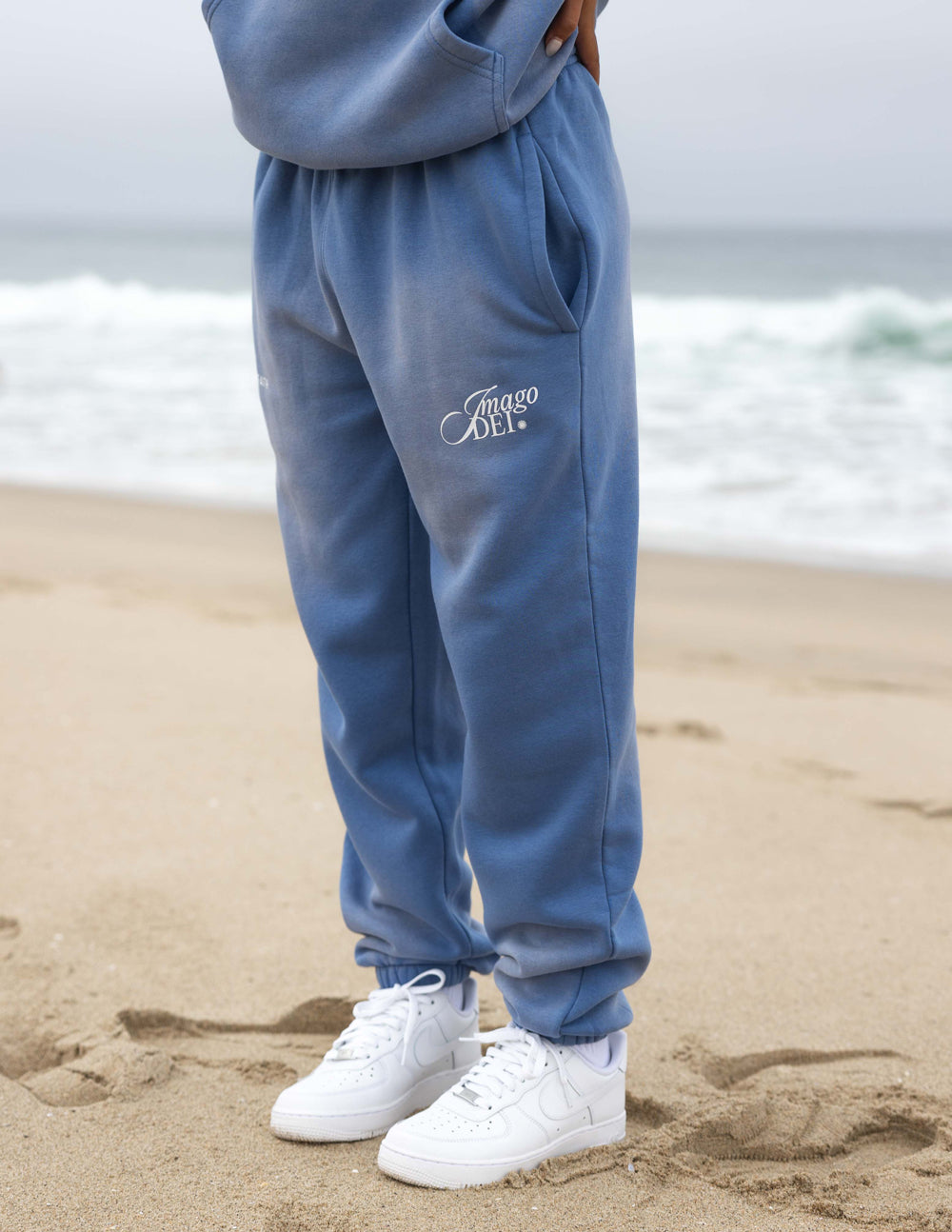 Blue unisex sweatpants with tapered legs, cuffed hems, and Imago DEI thigh logo