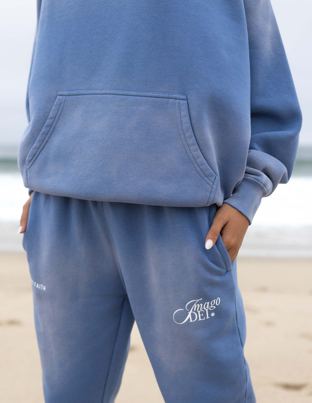 Blue unisex sweatpants showing back pocket and Imago DEI leg logo