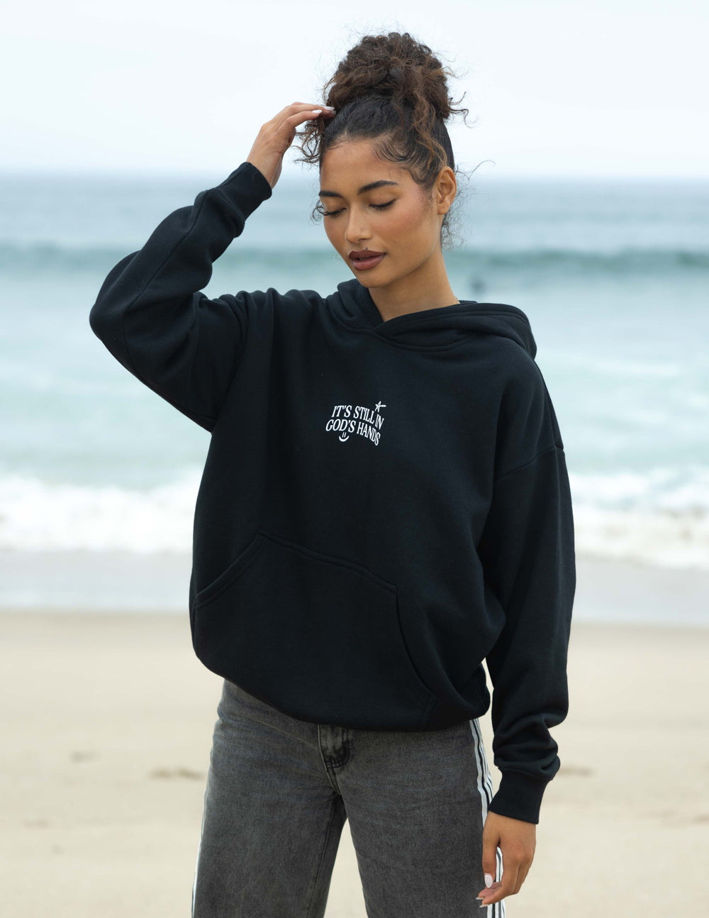 Black unisex hoodie with hood and small chest graphic, side pose
