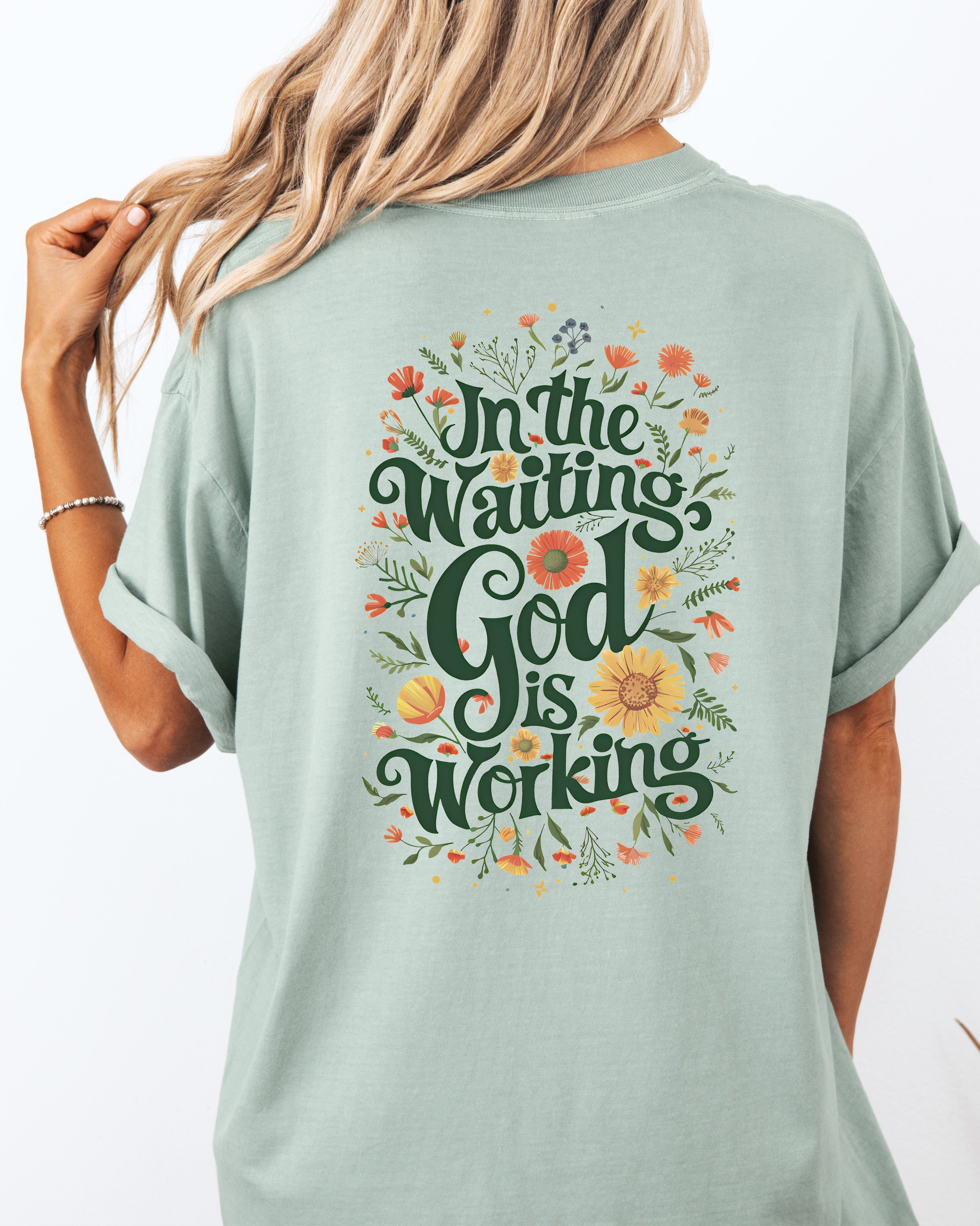 Light green T-shirt with floral 'In The Waiting God Is Working' graphic on back