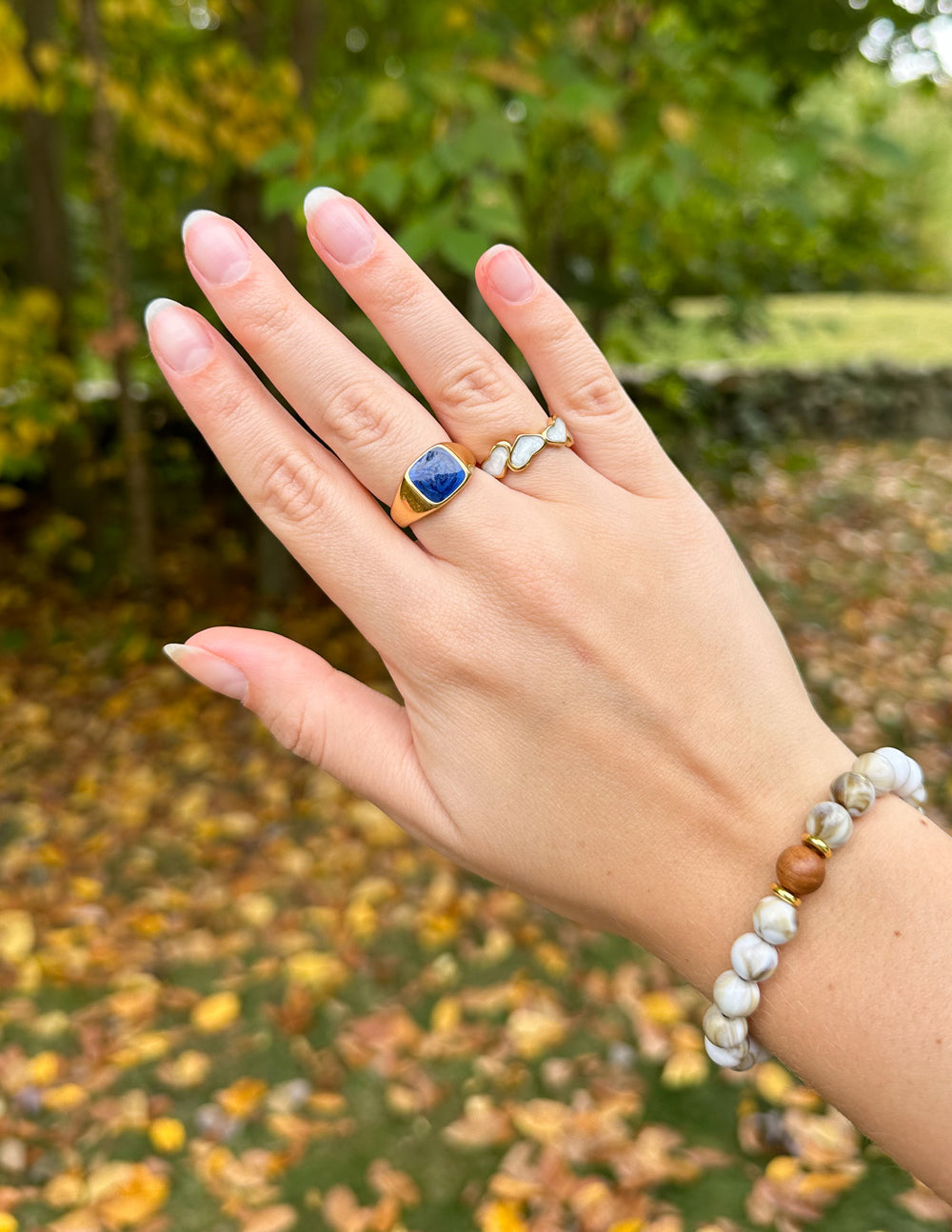 Gold signet ring featuring a dark blue square stone on hand