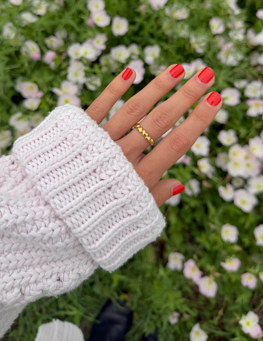 Gold band ring with scalloped infinity heart links on finger