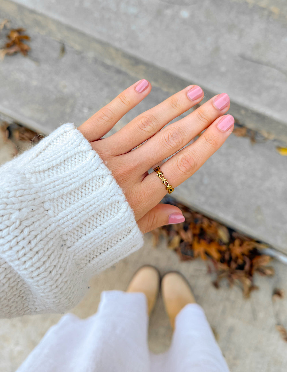 Gold infinity fish ring on hand, thin open band with fish motif.