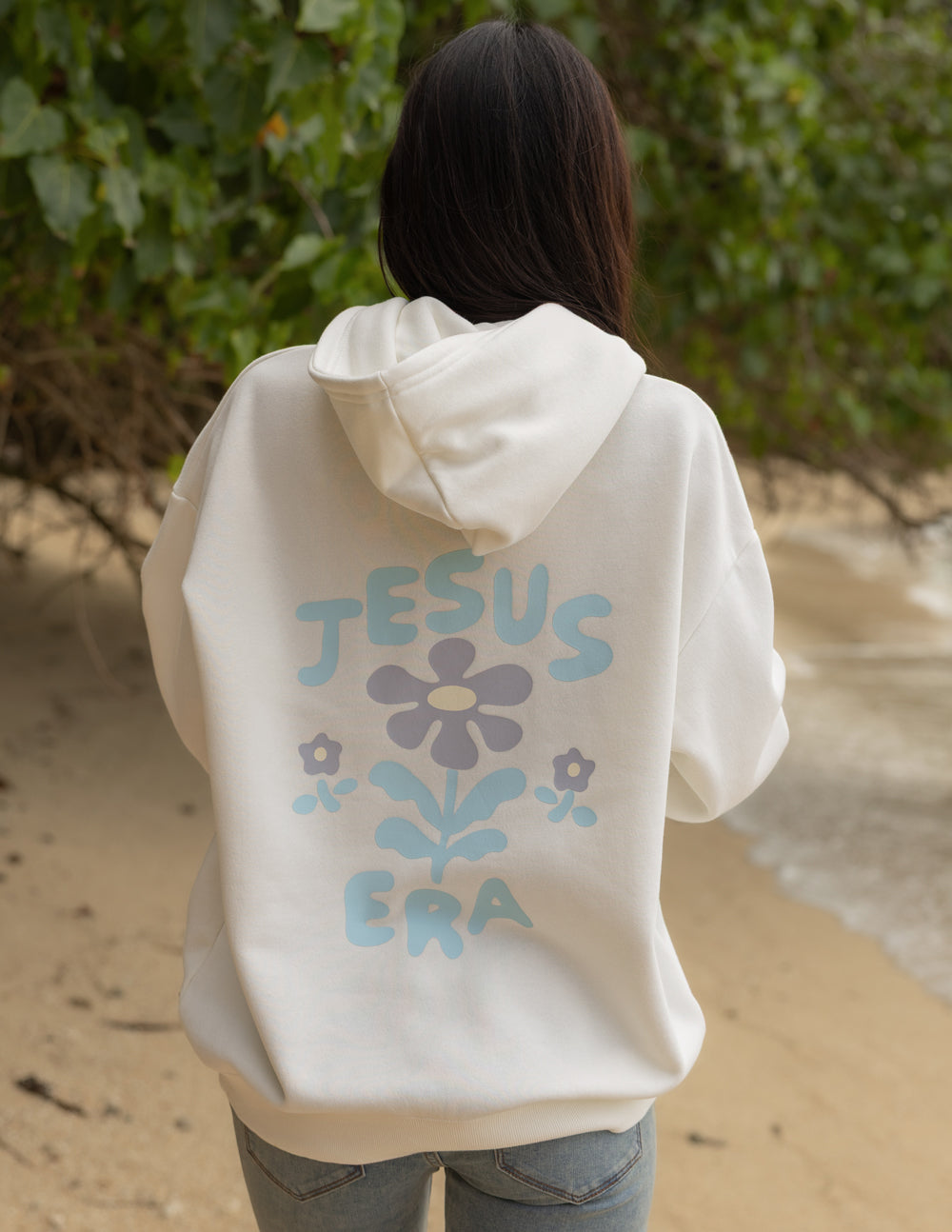 Cream unisex hoodie from behind with blue “JESUS ERA” back graphic and hood