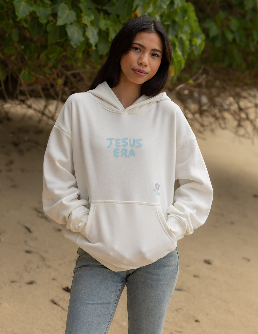 Cream unisex hoodie with blue “JESUS ERA” chest print, pullover hood, and front pocket