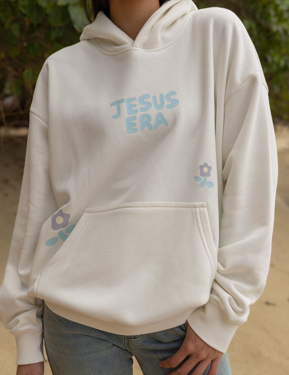 Off-white unisex hoodie with 'JESUS ERA' chest print and front kangaroo pocket detail