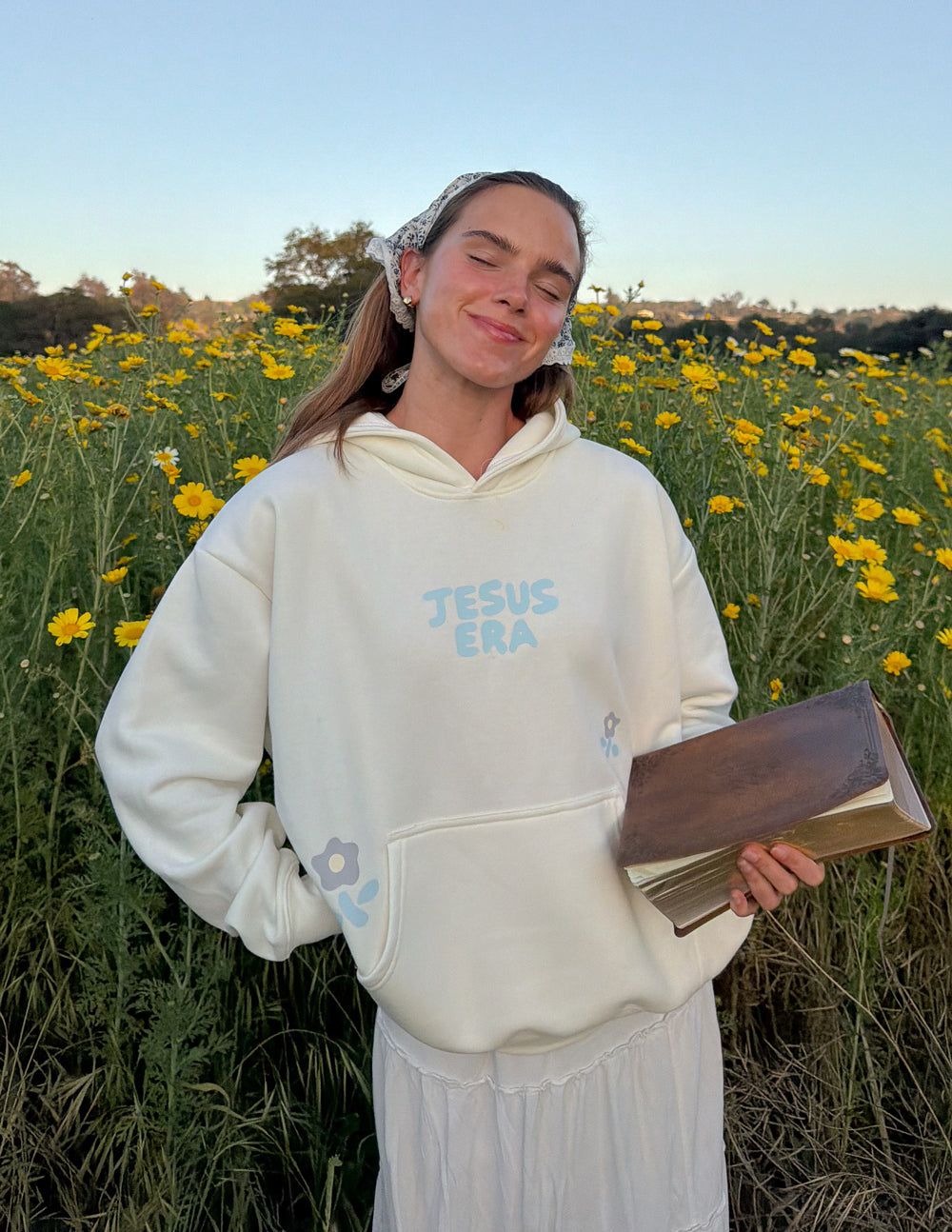 Unisex cream hoodie with blue “JESUS ERA” front print, pullover hood, and kangaroo pocket