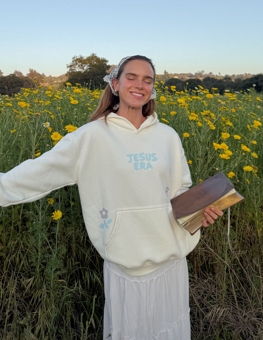 Cream unisex pullover hoodie with blue “JESUS ERA” logo on chest and front pocket