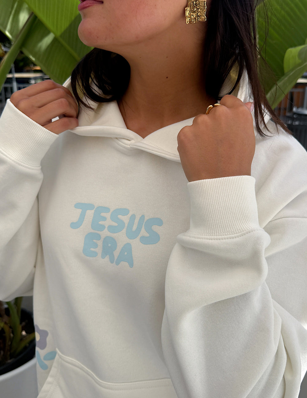 Off-white unisex hoodie close-up with 'JESUS ERA' chest graphic and hood