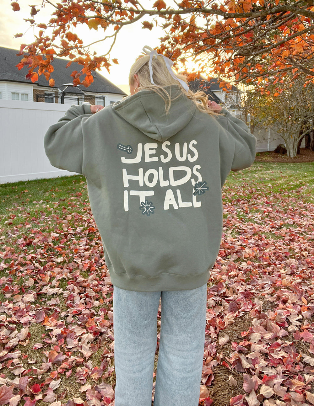 Sage green unisex hoodie with “JESUS HOLDS IT ALL” back graphic