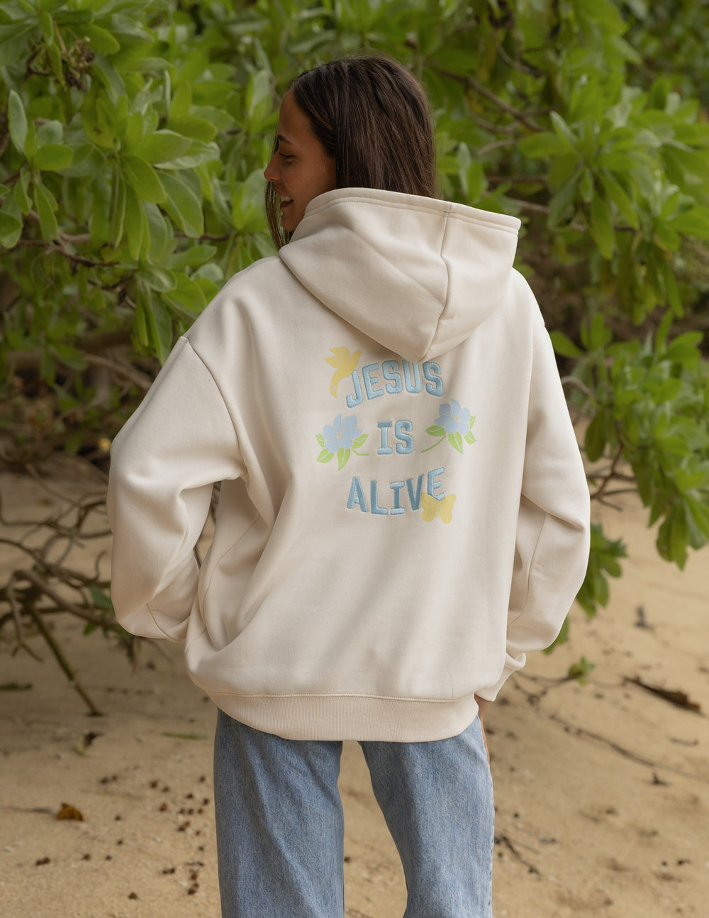 Unisex hoodie, cream, back graphic with “JESUS IS ALIVE” and colorful flowers