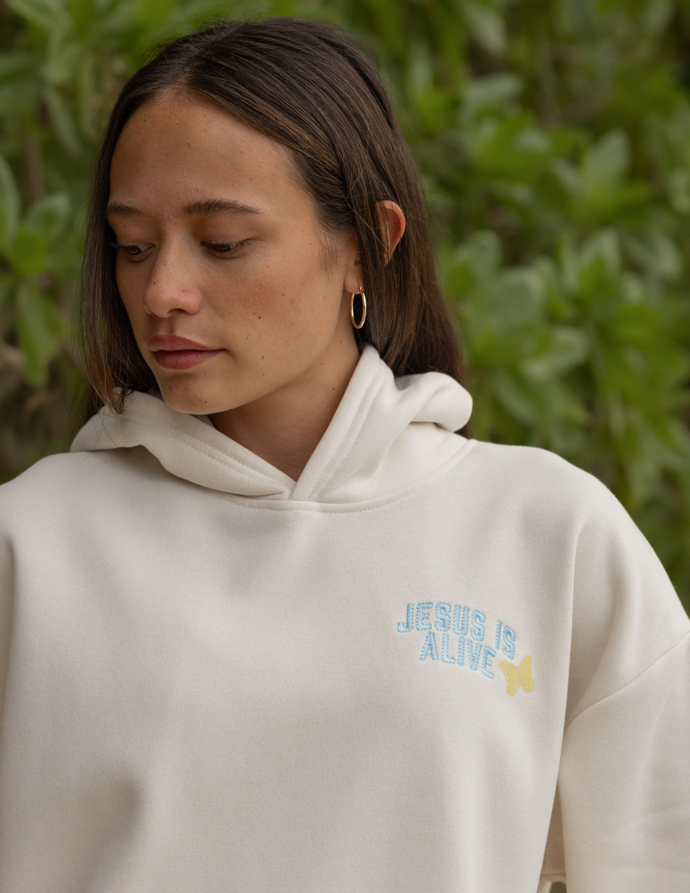 Unisex hoodie, cream, chest graphic text “JESUS IS ALIVE” with floral accents