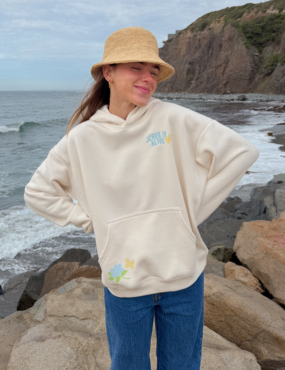 Unisex hoodie, cream, front view with hood and small “JESUS IS ALIVE” graphic