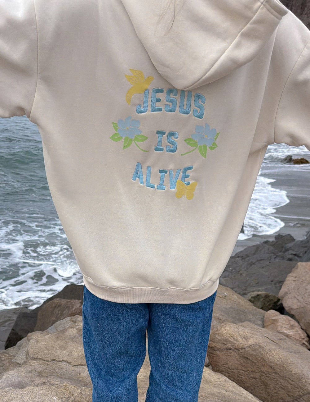 Unisex hoodie, cream, large back graphic “JESUS IS ALIVE” with flower accents