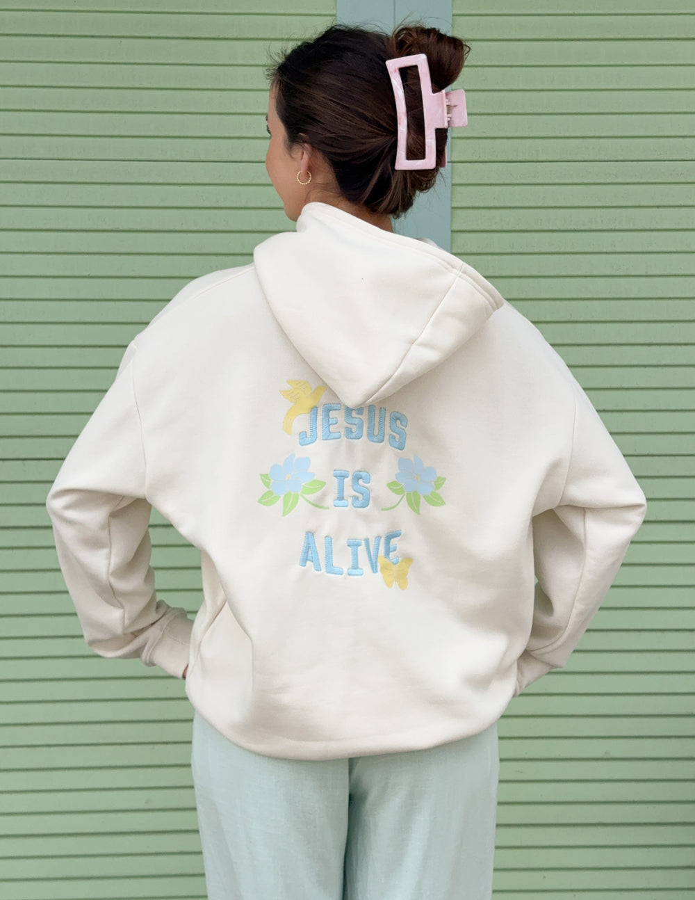 Unisex hoodie, cream, back graphic centered with “JESUS IS ALIVE” and floral details