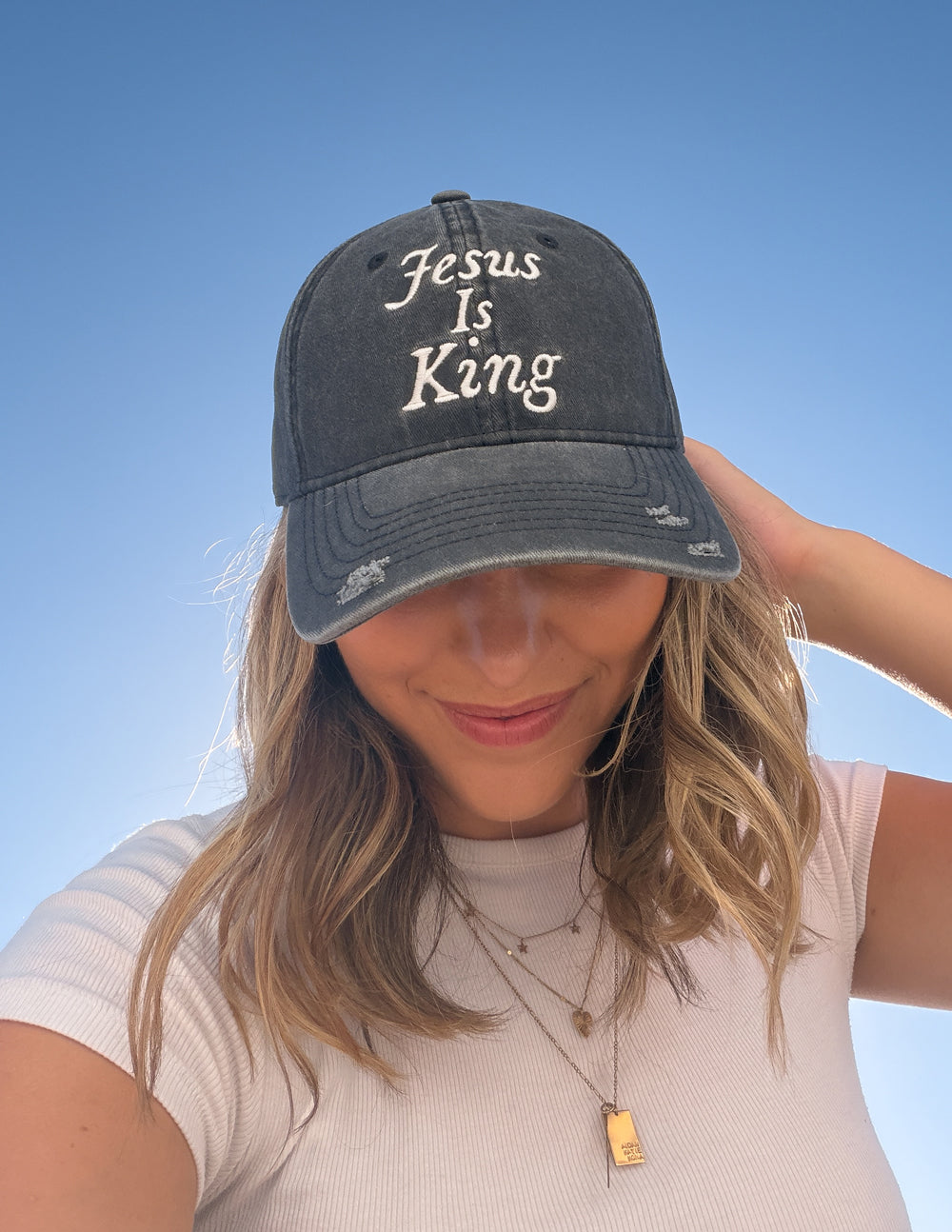 Black cap worn; front embroidery reads “Jesus Is King”