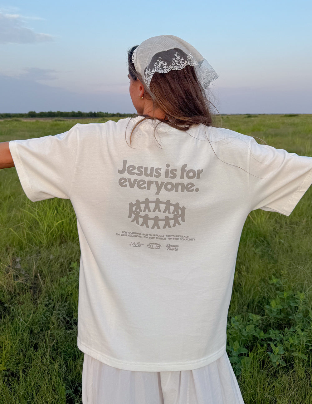 White heavyweight graphic T-shirt on woman with cap, back print centered