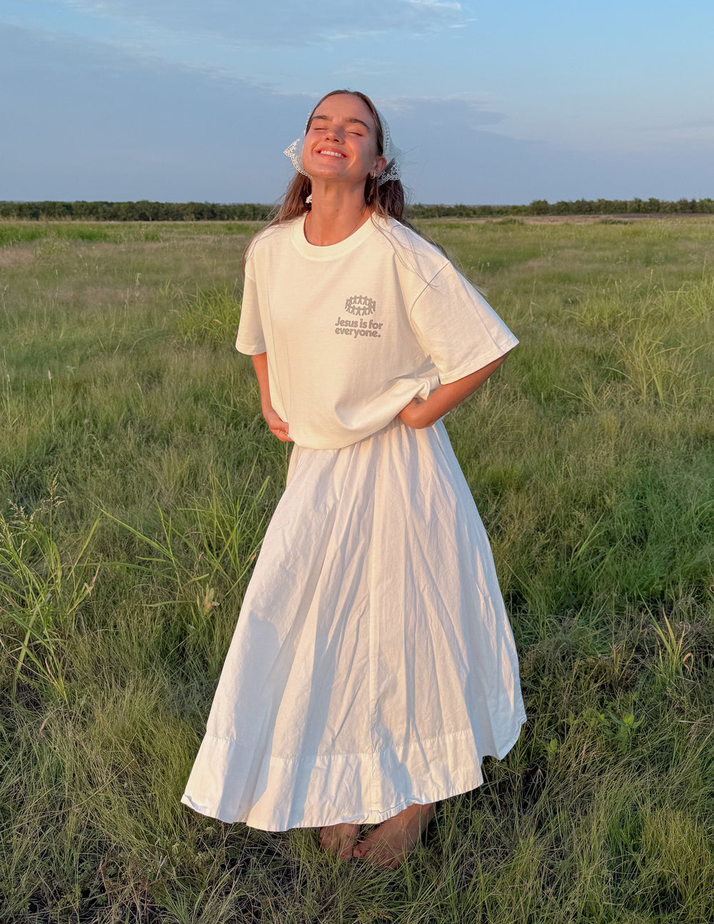 White heavyweight graphic T-shirt on model with skirt, front chest logo visible