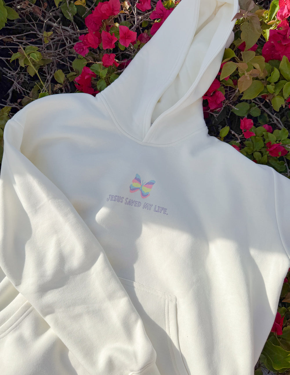 Unisex light hoodie with rainbow graphic and hood on, viewed from side