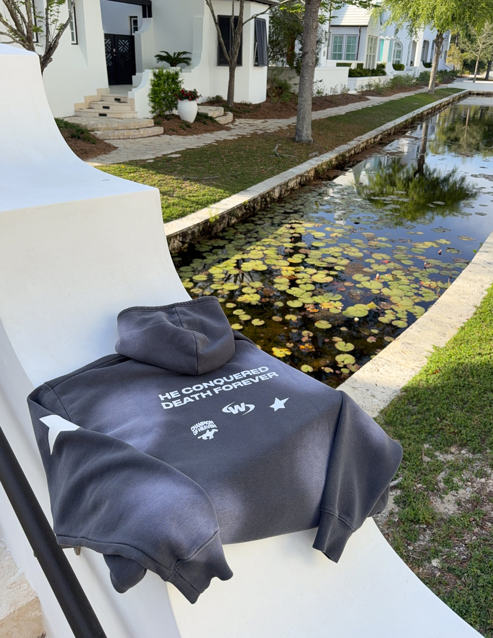 Dark gray unisex hoodie with hood and front pocket, back “THE CONQUERED DEATH FOREVER” print