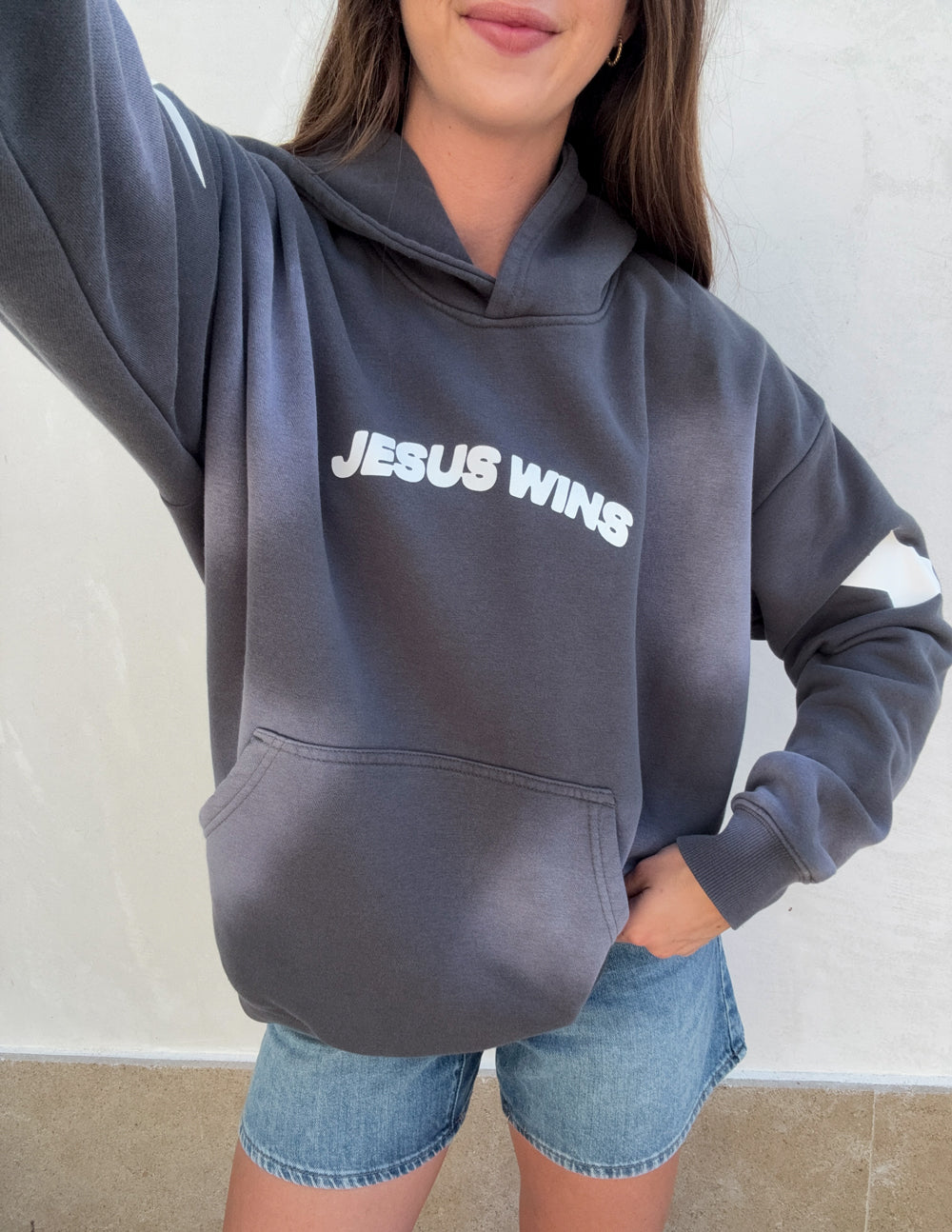 Dark gray unisex hoodie with 'JESUS WINS' chest print and kangaroo pocket.