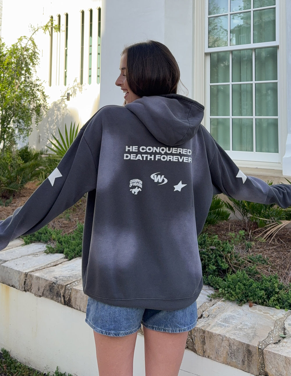 Dark gray unisex hoodie with 'HE CONQUERED DEATH FOREVER' back print.